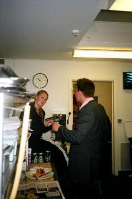 Formanden er færdig med sin beretning, og er gået i køkkenet for at drikke øl, imens Karen ser på
