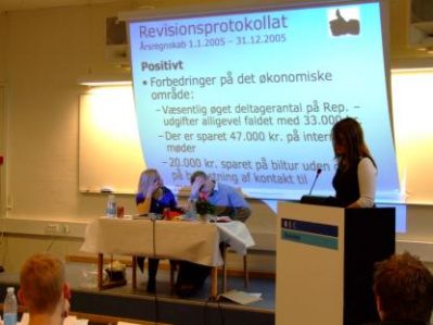 Den kritiske revision, her med Jeanne på talerstolen, fremlægger årsregnskabet
