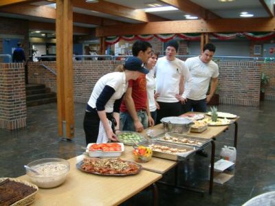 Karen er i gang med at gøre det sidste af frokosten klar, med et par sultne deltagere i baggrunden
